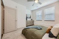 Inviting bedroom with modern decor, featuring a plush bed, elegant dresser, and ample natural light from large windows.