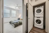 Contemporary apartment featuring a cozy bedroom with natural light and an in-unit washer and dryer, perfect for convenient living.