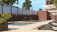 Modern outdoor pool area with sleek brick design, stylish lounge chairs, and elegant umbrellas offering a chic urban retreat.