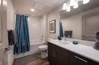 Modern bathroom with elegant dark wood vanity, stylish lighting, and a chic blue and white shower curtain.