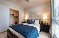 Cozy and inviting bedroom with modern decor, featuring a plush bed, stylish nightstands, and ample natural light from large windows.