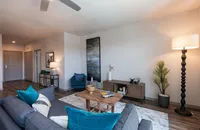 Inviting modern living room with elegant decor, featuring a comfortable gray sofa adorned with vibrant teal cushions, stylish wooden coffee table, and ambient lighting.