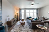 Chic modern living room with large windows, elegant decor, and a cozy dining area, offering ample natural light.