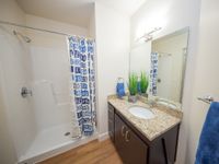 Modern bathroom with granite countertop, sleek dark wood cabinetry, vibrant blue decor, and a chic shower curtain.