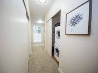 Bright hallway with elegant artwork and in-unit laundry, leading to a sunlit window view.