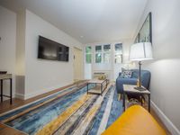 Chic living room with modern decor, featuring a stylish sofa, sleek flat-screen TV, and a vibrant striped rug creating a warm ambiance.