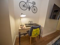 Contemporary study nook with a chic desk, elegant lamp, and wall-mounted bicycle art, perfect for a modern apartment vibe.