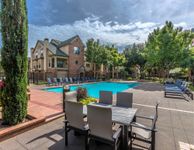 Elegant apartment complex with inviting pool area, surrounded by lush greenery and modern outdoor seating, perfect for relaxation and gatherings.