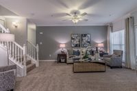 Chic living room with elegant decor, plush carpeting, stylish armchairs, and a modern staircase.