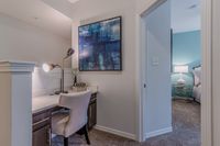 Chic apartment study nook with sleek desk setup, elegant artwork, and cozy bedroom glimpse, perfect for modern living.