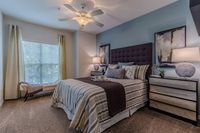 Inviting bedroom with elegant decor, plush bedding, and ample natural light through large window.