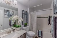 Elegant bathroom featuring modern fixtures, vibrant artwork, plush towels, and a stylish vanity with decorative orchids for a tranquil atmosphere.
