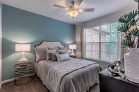 Inviting bedroom with elegant decor, featuring a cozy bed with plush pillows, vibrant teal accent wall, and large window for natural light.