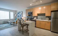 Seamlessly Connected Living & Dining Modern apartment kitchen with sleek cabinetry, island dining, and open living space, featuring abundant natural light and contemporary decor.