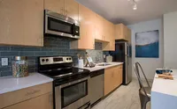 Where Style Meets Function Modern kitchen with sleek stainless steel appliances, stylish wooden cabinets, and contemporary tile backsplash, creating a warm and inviting culinary space.