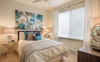 Sleep In, Stretch Out Inviting bedroom with modern decor, featuring a cozy bed, abstract art, and natural light through large windows.