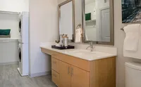 Refresh & Rejuvenate Modern bathroom with sleek wooden vanity, elegant mirrors, and in-unit laundry for convenient living.