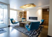 Your Space for Social Moments Modern lounge area with sleek blue chairs, cozy fireplace, and elegant decor, perfect for relaxation and socializing.