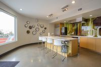 Sip, Chat, Repeat Modern kitchen with a sleek island, stylish bar stools, and vibrant backsplash, offering ample natural light through a large window.