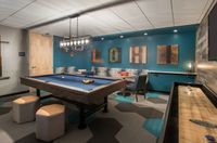 Game On, Anytime Chic game room featuring a stylish pool table, modern lighting, playful artwork, and a cozy seating area with vibrant decor.