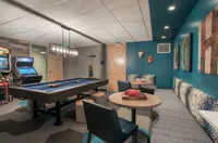 Lounge, Laugh, Level Up Chic recreation room featuring a sleek pool table, cozy seating area, and vibrant arcade games, perfect for entertainment and relaxation.