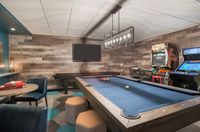 Your Built-In Entertainment Zone Chic entertainment room featuring a sleek pool table, stylish seating, and classic arcade games under ambient lighting.