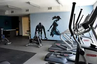 Sweat, Sculpt, Repeat Contemporary fitness center equipped with state-of-the-art treadmills and spin bikes, featuring a dynamic wall mural for motivation.