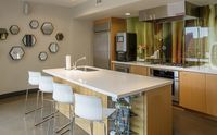 Fuel up on-site Modern kitchen with sleek white countertops, warm wood cabinets, and chic geometric wall decor.