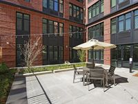 Modern apartment courtyard with stylish outdoor seating, sleek brick facade, and ambient string lights for a cozy atmosphere.