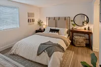 Cozy Bedrooms, Peaceful Nights Inviting bedroom with elegant decor, featuring a cozy bed, stylish wall art, and a chic vanity with a round mirror.
