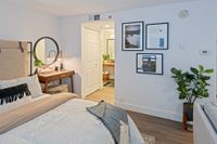 Designed with You in Mind Charming bedroom with stylish decor, featuring a comfortable bed, wooden desk with modern lighting, framed artwork, and lush indoor plant, creating a cozy and inviting atmosphere.