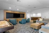 The Hangout Spot You’ll Brag About Modern lounge area with comfortable seating, large TV, and elegant wood accents, perfect for relaxation or entertaining.