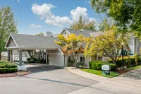 More Than a Home—It’s a Way of Life Charming apartment community with a welcoming entrance, lush greenery, and a well-maintained drive-up area under a clear blue sky.