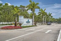 Welcome to River North Apartments Inviting entrance to River North Apartments framed by lush palm trees and vibrant flowerbeds under a clear blue sky.