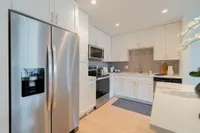 Where Style Meets Function Modern kitchen with sleek stainless steel appliances, elegant white cabinetry, and sophisticated gray backsplash.