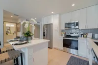 Designed to Inspire Every Mea Modern kitchen with sleek stainless steel appliances, elegant white cabinetry, and a chic breakfast bar adorned with fresh orchids.