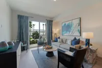 Modern Layouts, Natural Lig Inviting living room with elegant decor, featuring a cozy sofa, abstract artwork, and bright natural light from large windows overlooking a lush garden.