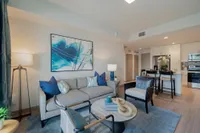 Spacious. Stylish. Bright. Bright and modern open-concept living space with elegant decor, featuring a cozy seating area, sleek kitchen, and stylish bar stools.