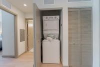 Laundry, But Make It Stylish Modern apartment hallway featuring a convenient in-unit stacked washer and dryer within a sleek closet space.