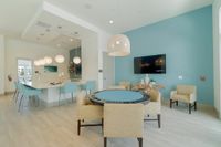 Game Room Goals, Achieved Contemporary open-plan living area featuring sleek kitchen island with pendant lights, stylish round dining table, and modern decor against a soothing blue accent wall.