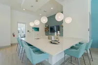 Your Built-In Entertainment Zone Elegant modern kitchen with a large marble island, stylish pendant lighting, and plush blue bar stools, perfect for entertaining.
