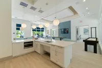 Lounge, Laugh, Level Up Modern open-concept kitchen with sleek countertops, stylish pendant lighting, and spacious seating area overlooking a vibrant garden view.