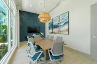 Tech-Ready, Task-Friendly Modern conference room featuring elegant wooden table, stylish rolling chairs, large windows with outdoor view, decorative ocean-themed art, and contemporary pendant lighting.