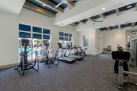 Fitness on Your Schedule Modern fitness center with state-of-the-art treadmills and exercise bikes overlooking a sunny pool area.