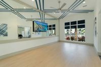 Move. Motivate. Maintain. Modern exercise room with mirrored walls, ceiling fans, and vibrant artwork, perfect for a dynamic workout experience.