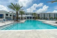 Poolside Vibes, All the Time Luxurious apartment complex with a stunning resort-style pool, elegant poolside loungers, and beautiful palm trees under a bright blue sky.