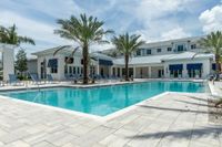 Your Private Slice of Paradise Luxurious modern apartment complex with a stunning swimming pool, surrounded by palm trees and lounge chairs, under a beautiful blue sky.