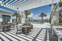 Cookout-friendly zones Luxurious outdoor pool area with stylish seating, palm trees, and modern architecture under a clear blue sky.