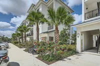 Beautifully Landscaped, Thoughtfully Designed Modern apartment building with lush palm trees and vibrant flowers, featuring sleek balconies and reserved parking in a sunny location.
