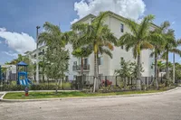 Welcome to Life at River North Bright and modern apartment building surrounded by lush palm trees and a colorful playground, offering a perfect blend of tranquility and family-friendly amenities.